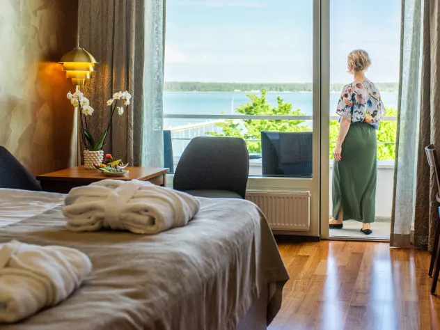 Hotellrum med kvinna stående på rummets balkong.
