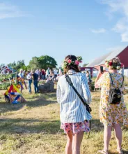 Kvinna fotograferar lövning av stången vid midsommarfirande på Bergö.